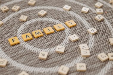 An artistic display of Scrabble tiles spelling 'FAMILY' on a textured carpet surface.