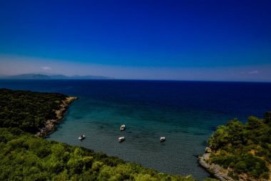 A stunning aerial view of the coastline at Güzelçamlı, Türkiye, featuring lush greenery and clear blue waters.